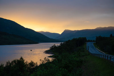 Scenic view of river and mountains against sky during sunset