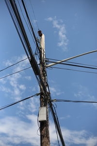 Low angle view of bird perching on electricity pylon against sky