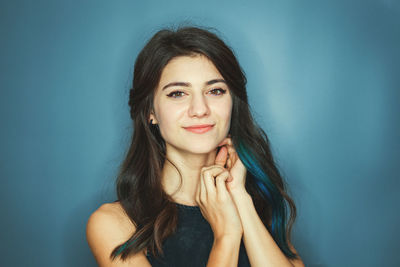 Smiling brunette with blue strands of hair woman looking directly at the camera