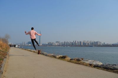 Rear view of man standing by sea against sky