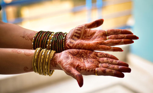 Cropped hands of woman wearing bangles showing henna tattoo at home