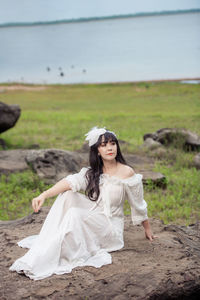 Beautiful young woman lying on land against sky