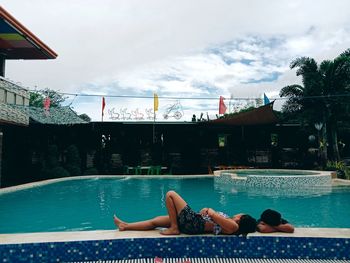 Woman relaxing in swimming pool against sky