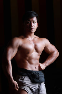 Portrait of young man standing against black background