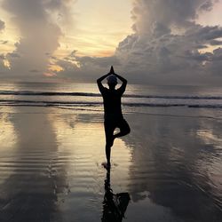 Rear view of a guy standing at the beach during sunset