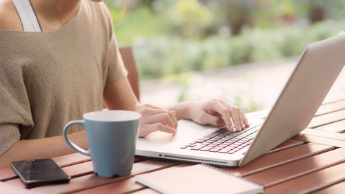 Midsection of businesswoman using laptop on table