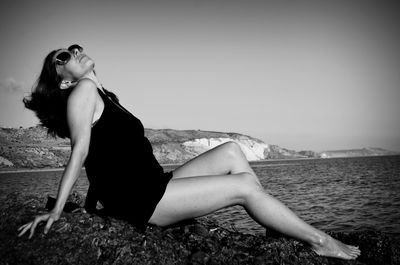 Portrait of woman sitting on beach against sky