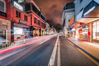 Light trails on street amidst buildings in city at night