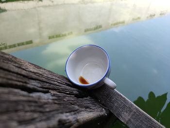 High angle view of tea cup on table by lake