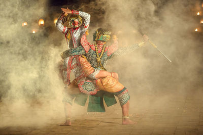 Midsection of man dancing in traditional clothing at night