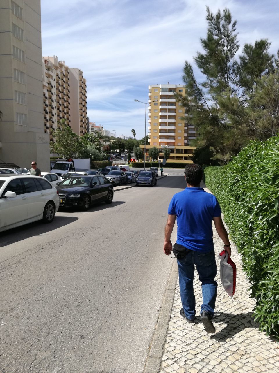 architecture, car, rear view, walking, built structure, real people, street, building exterior, tree, day, outdoors, one person, land vehicle, road, city, full length, sky, people