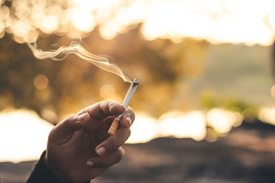 Close-up of hand holding cigarette