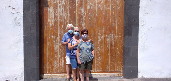 Portrait of senior friends standing against wooden wall