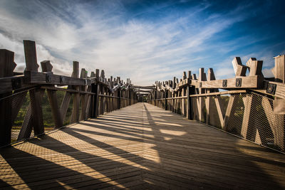 Wooden footbridge against sky