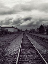 Railroad tracks against cloudy sky