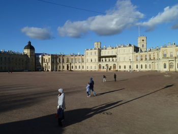 People walking on historic building against sky