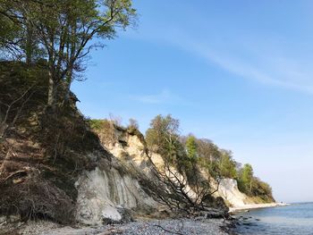 Scenic view of rocks by sea against sky