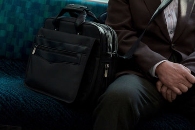 Midsection of man sitting with bag on sofa