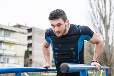 Young man exercising amidst railing against sky