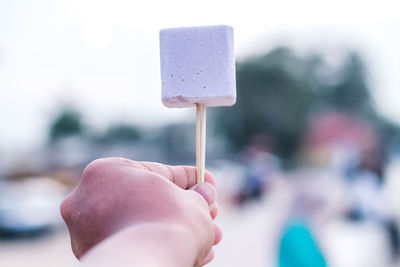 Close-up of hand holding ice cream cone against blurred background