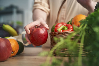 Midsection of woman holding fruits on table