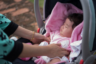 Cropped hands of mother keeping daughter in baby stroller