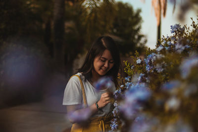 Portrait of a young woman standing against plants