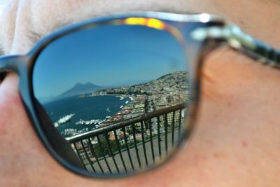 Sea and cityscape reflecting on person sunglass