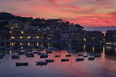 Boats moored in canal against buildings at sunset