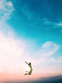 Low angle view of man jumping against sky