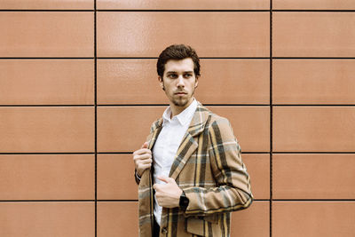 Portrait of young man standing against wall