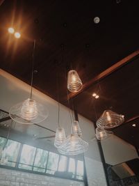 Low angle view of illuminated lighting equipment hanging against sky