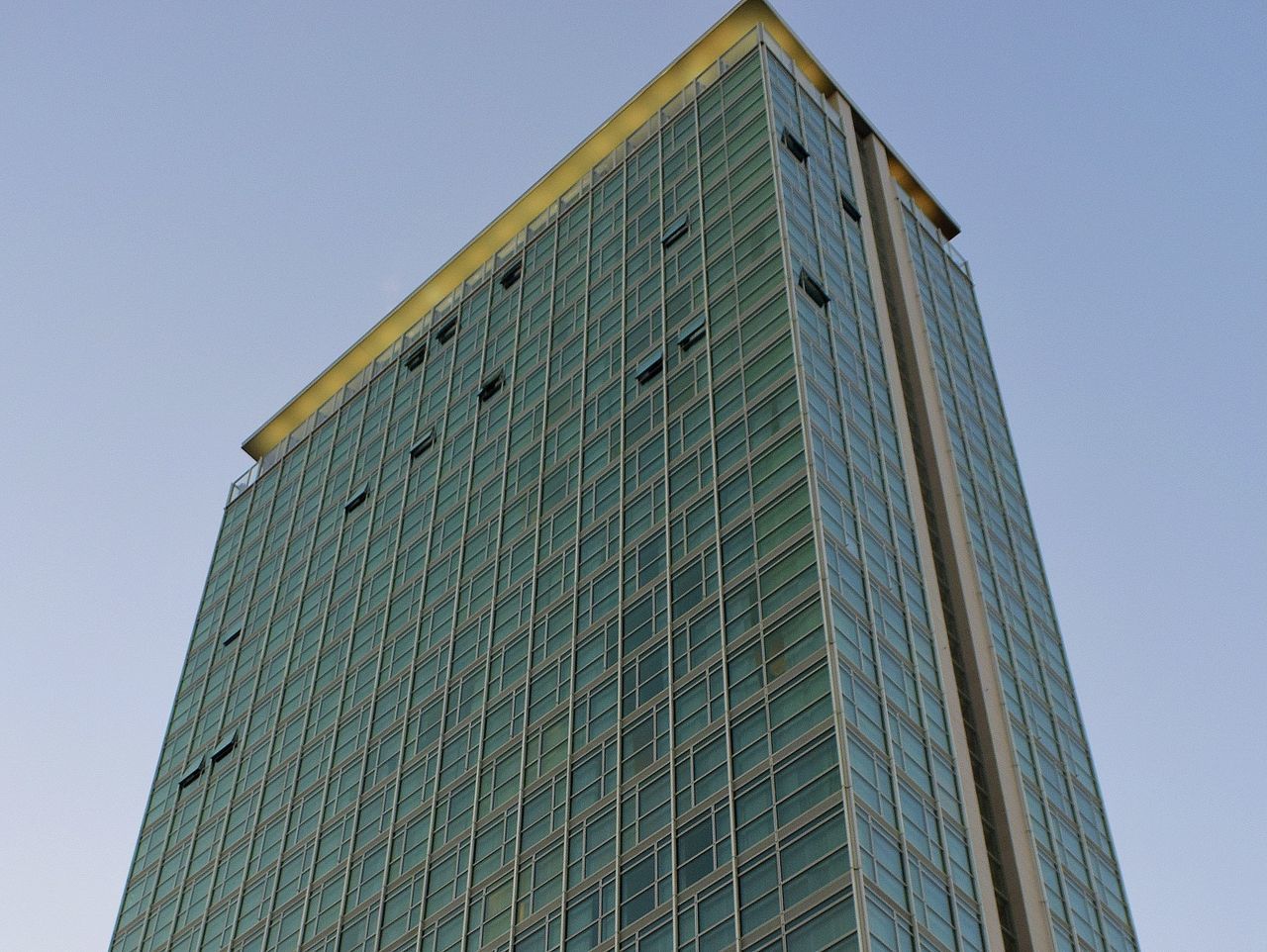 LOW ANGLE VIEW OF MODERN GLASS BUILDING AGAINST CLEAR SKY