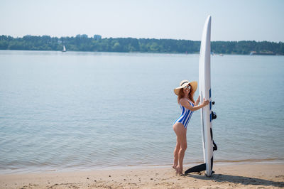 Low section of woman standing on beach against sky