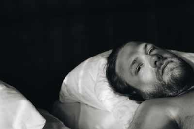 Portrait of man lying against black background