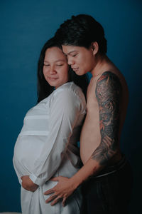 Happy couple standing against blue background