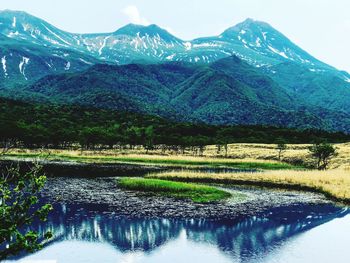 Scenic view of lake by mountains against sky