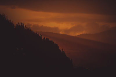 Scenic view of silhouette mountains against orange sky