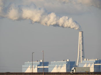 Smoke emitting from factory against sky