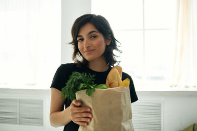 Portrait of young woman holding while standing at home