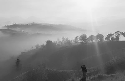 Silhouette man standing on mountain against sky during sunny day