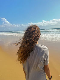 Woman standing on beach against sea against sky