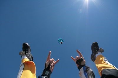 Low angle view of people flying against clear blue sky