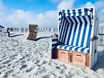 Hooded chairs on beach against sky