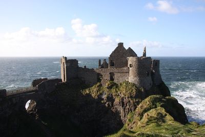 Fort on cliff by sea against sky