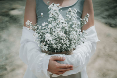 Midsection of woman holding white flower