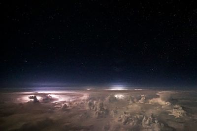 Aerial view of illuminated sea against sky at night