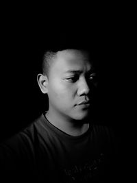 Close-up portrait of cute boy against black background