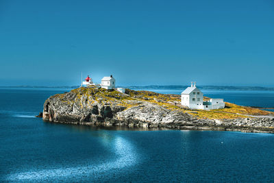 Lighthouse amidst sea and buildings against sky