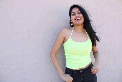 Portrait of beautiful young woman standing against wall